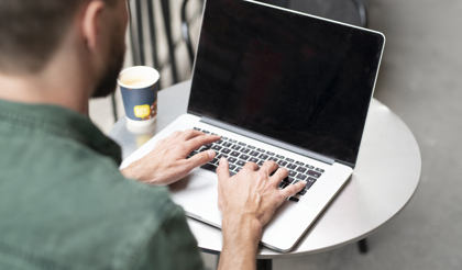 Bild på person som sitter framför en bärbar dator. 